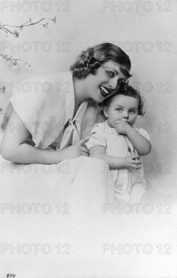 Mother with child, 1930s, Woman and small child sitting next to each other and laughing in a studio