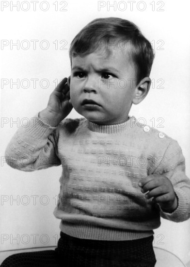 Annoyed child, 1950s, A little boy in a jumper with a questioning expression holds his hand to his