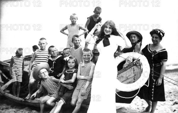 Children's leisure time, 1920s, children in striped clothes and a woman posing smiling on the beach