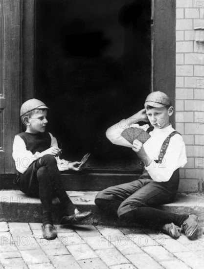 Two children playing cards, 1930s, Two boys in period clothing playing cards on a staircase,