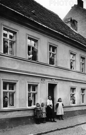 People looking out of windows, 1920, people in a house looking out of windows and standing outside,