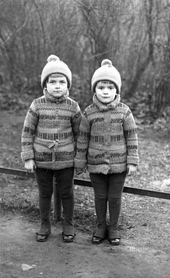 2 boys, twins, 1920, Two identical children in winter clothes standing next to each other outdoors,