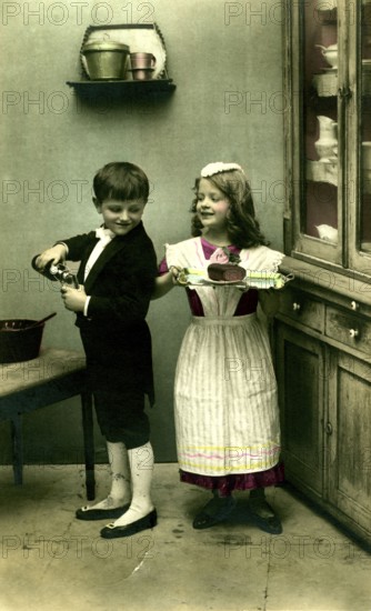 Boy and girl as servants, 1920s, A boy and a girl playing in an old kitchen with apple juice and