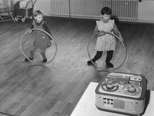 Two children playing with the Hulahup tyre, 1950s, Two girls dancing with tyres in front of a tape
