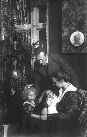 Christmas Eve, 1920s, family in the living room with Christmas tree and candles, festive
