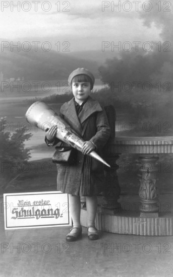 School enrolment, 1920s, A boy with a school bag poses in front of a picturesque landscape,