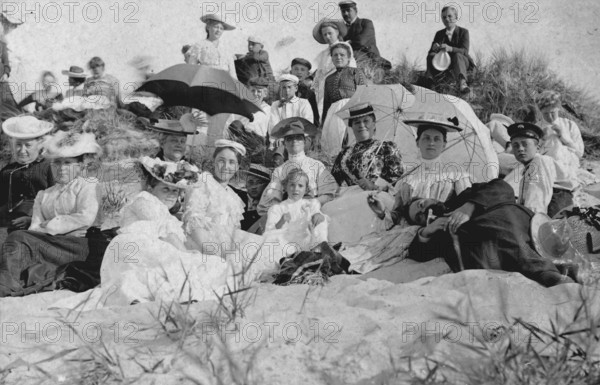 Large group of holidaymakers sitting in dunes, 1910s, Group of woman and men sitting on a sunny