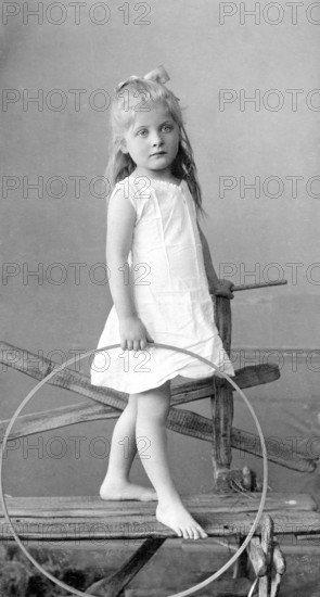 Girl around 1900, Young girl posing with a tyre, barefoot and smiling into the camera, Historical