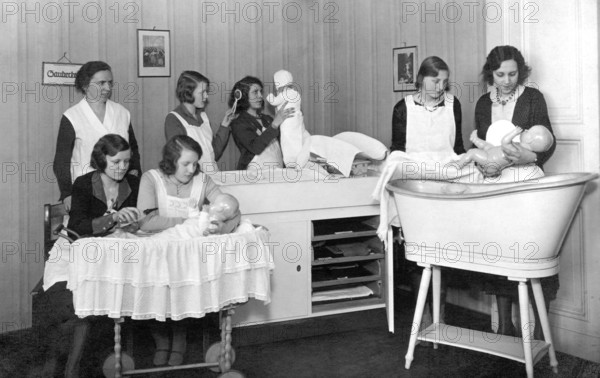 Midwifery school, 1930s, woman in uniforms, caring for dolls in a classical room, training