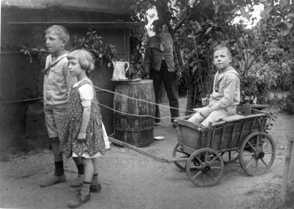 Children playing with carts, 1920s, children pulling a wooden cart in the garden, playful and
