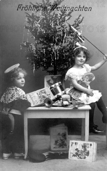 Boy and girl under a Christmas tree, 1930s, Two children sitting in front of a Christmas tree with