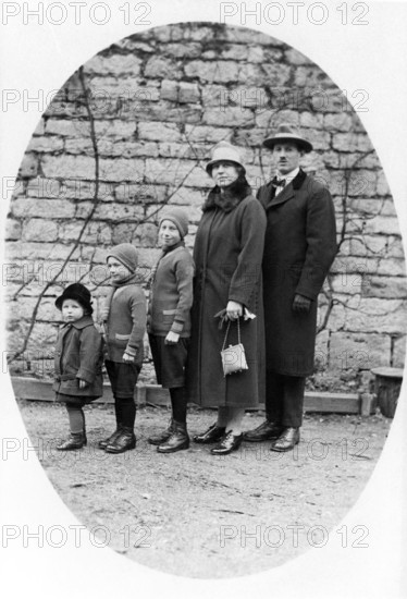 Family standing in a row, 1930s, Family in winter clothes standing together in front of a stone
