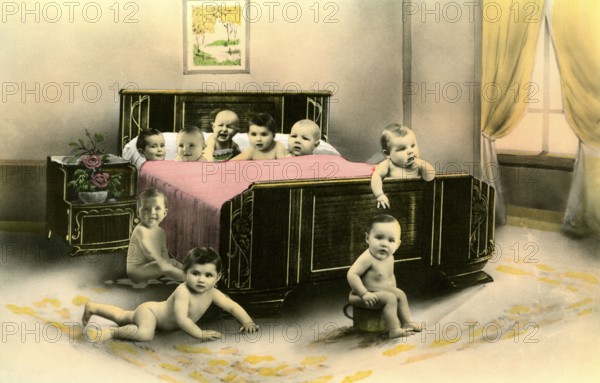 Nine babies in a bed, 1920s, Several babies crawling curiously around a large bed in a room,