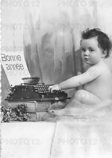 Baby writing at a typewriter, 1920s, A baby sits next to a typewriter with a French greeting,