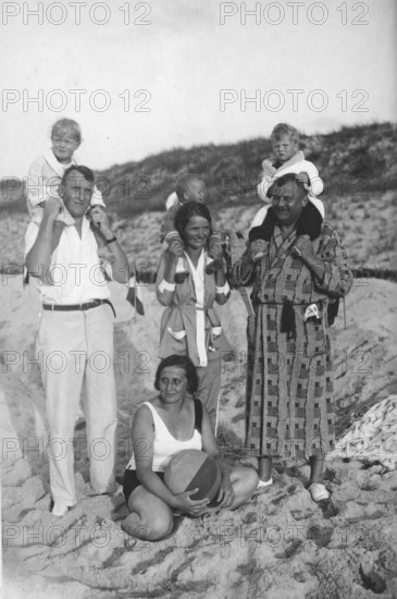 Family on the beach, 1920s, family photo on the beach with adults and children, children sitting on