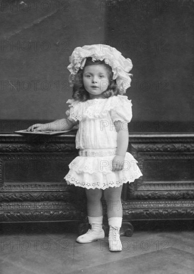 Little girl in dress, 1920s, Little girl in lace dress and hat posing in front of piece of
