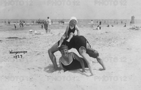Family on the beach, Wangerooge 1927, An adult lies on the beach while a child sits on his back.