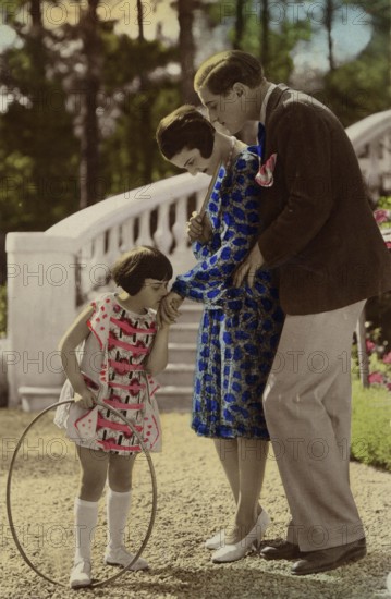 Girl kissing woman's hand, 1920s, child with a ring playing happily, watched by parents in the