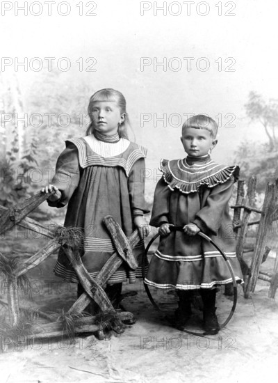 Two girls in Sunday dresses, 1920s, Two children in old-fashioned clothes in front of a painted