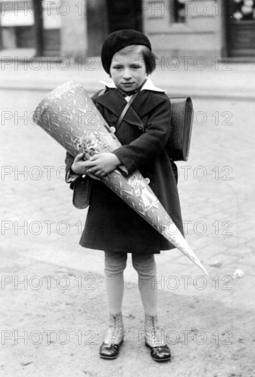 Little girl with school cone, 1940, A child in school uniform holding a large sugar cone on the