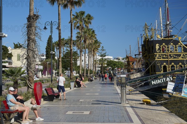 Promenade with palm trees and a sailing ship in the background, relaxed atmosphere, harbour
