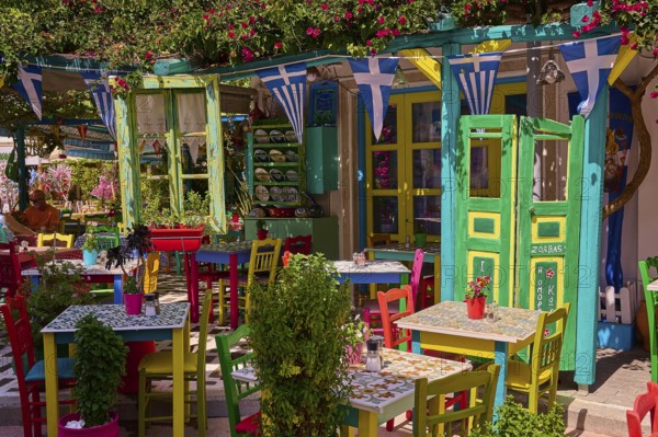 Colourfully decorated taverna with open doors and plants, summery and friendly atmosphere, Platia