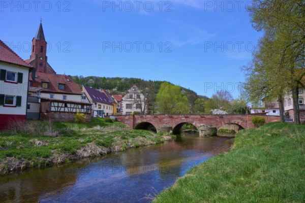 Picturesque small town view with river Saale, bridge and half-timbered houses under blue sky,