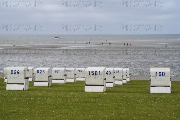 Beach chairs on the green beach, walker on the mudflats, fishing boat, Büsum, North Sea,