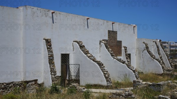 ©Udo Rein, White antique building with exposed stone walls under a blue sky, exterior view, Casa