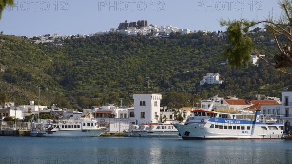 Harbour with ferries in front of green mountains and blue sea, town on the shore, Skala, harbour,