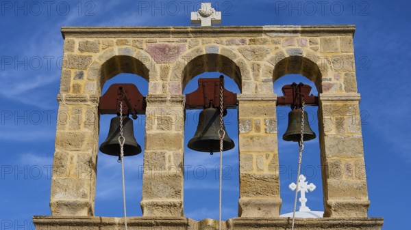 Church of Agios Ioannis Prodromos, Triple bell tower made of stone with blue sky in the background,