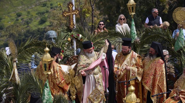 Priests in elaborate robes and incense burners stand in the light of numerous candles during a