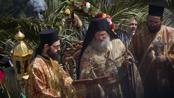 Priests in magnificent robes celebrate a religious ritual surrounded by palm trees and a festive