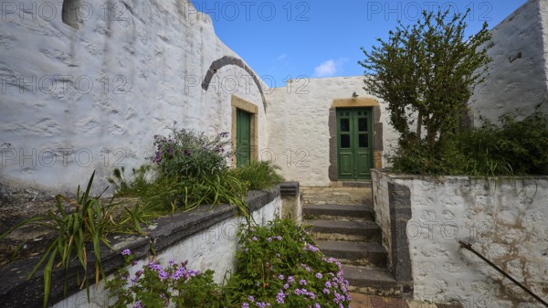 Inner courtyard with whitewashed walls, green doors and flowering plants, Monastery of the