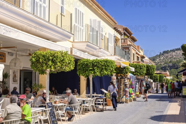 Outdoors restaurant on a street with tourist sitting in the sunshine in an idyllic village, Sant