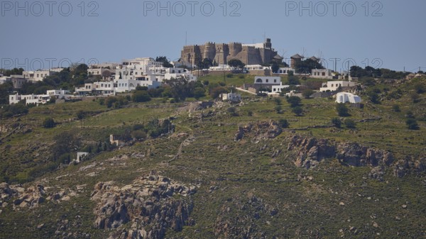 Village on a hill with stone houses and green landscape under a clear sky, Monastery of St John the