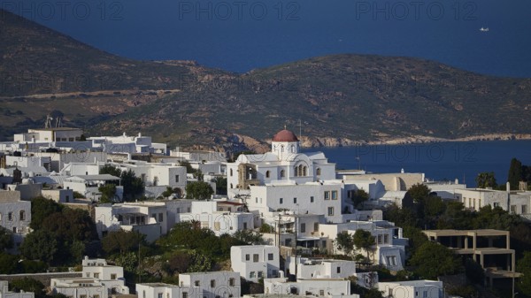 Whitewashed church with red roof in front of a coastal landscape and blue sea, World Heritage Site