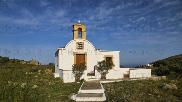 White chapel with bell tower in a rural, Mediterranean setting under a blue sky, chapel south of