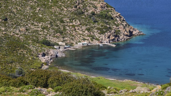 Small harbour bay with crystal clear water surrounded by rocky landscape and lots of greenery,