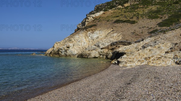 Stone beach under clear blue sky with coastline and water, Lambi Beach, Lambi Bay, Patmos,