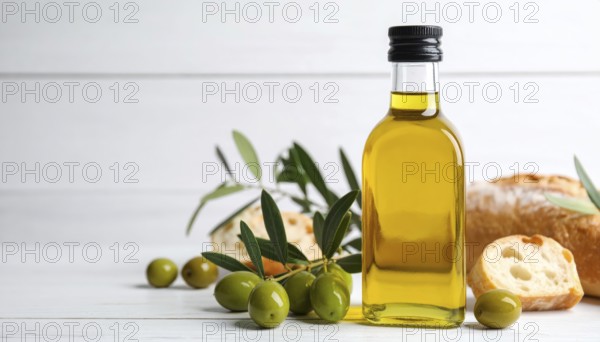 Bottle of fresh olive oil with branch with green olives and ciabatta, closeup, white wooden table,