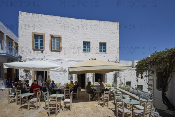 People sitting at tables under parasols on a sunny café terrace, Platia Lesvias, Chora, UNESCO