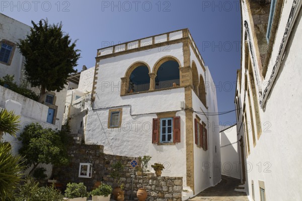 White house with striking balcony and brick details under a clear blue sky, Lion's Alley, Captain's