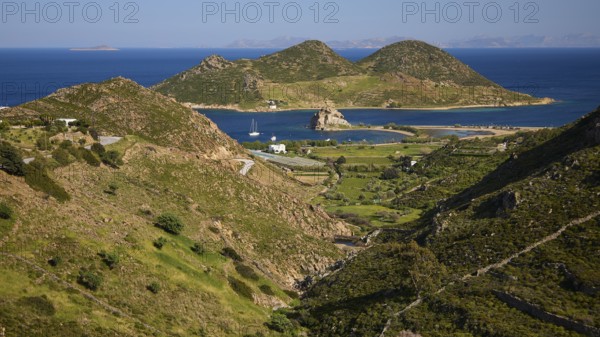 Hilly landscape with fields and coast, green and blue dominate the view, rocks of Kalikatsou,