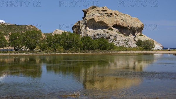 Elevated rock with its reflection in the calm lake on a sunny day, Seasonal salt lake, Rock of