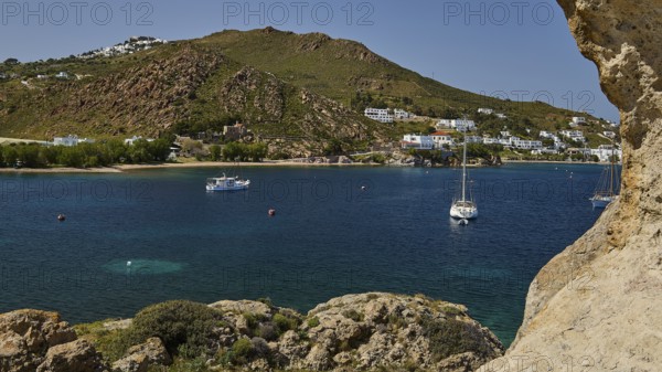 Coast with houses and boats on the calm sea, surrounded by hills and rocks, cave, rocks of