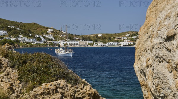 Sailing boat in a bay, surrounded by rocks and white buildings on the shore, Grikos, Rock of