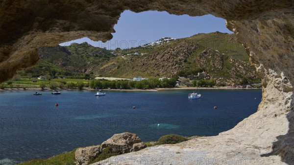 View from a cliff to the calm sea with boats and a green hilly coastal scene, cave, Chora, Grikos,