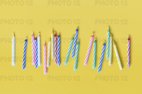 Colorful birthday candles in a row on yellow background