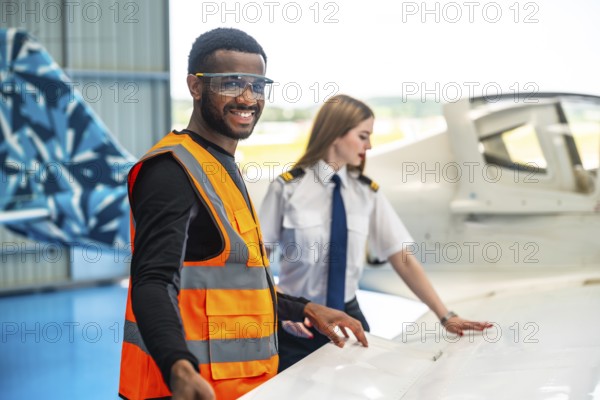 Smiling aircraft maintenance engineer and pilot inspecting airplane wing, ensuring safety and